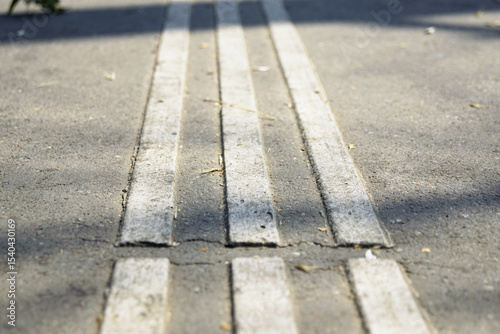 Close-up of tactile paving with raised textured lines on a asphalt sidewalk. Concept of inclusive city design, accessibility for visually impaired pedestrians and urban planning for all
