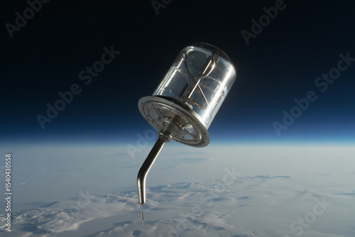 A clear container with a metal tube extending from it in space above clouds and the earth horizon