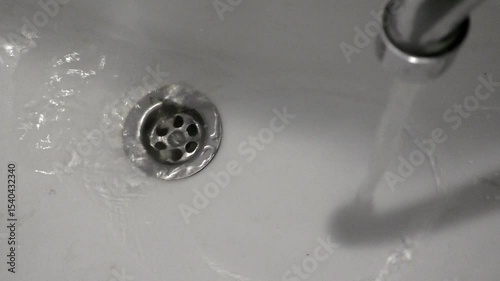 Water is pouring into the sink from the faucet. The bathroom detail.