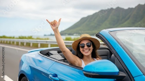 Joyful Young Woman In Sunglasses Smiling While Gesturing From A Blue Convertible Car On A Coastal Road
