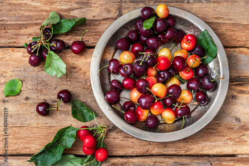 Ripe, sweet cherries in a plate on a wooden table