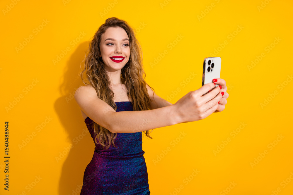 Young fashionable woman taking a selfie with a smartphone against a vibrant yellow background in a trendy dress Young fashionable woman taking a selfie with a smartphone against a vibrant yellow background in a trendy dress