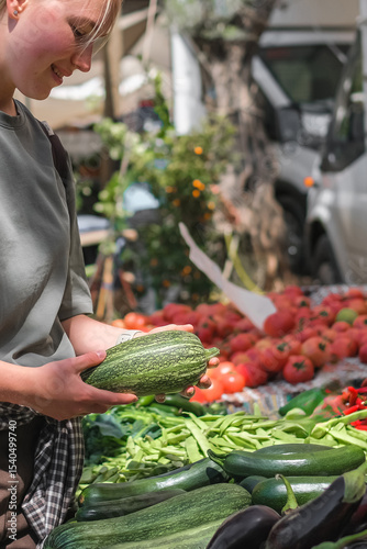 Young woman choosing fresh organic vegetables at a local market. Concept of eco lifestyle, sustainable food, mindful consumption, zero waste, farm produce, and conscious living.