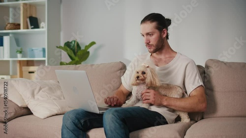 Emotional Support, Mental Health, Work-Life Balance. Young Man Works from Home, Focused on Online Meeting While His Dog Sits Beside. A Calm Moment of Digital Connection and Pet-Driven Stability