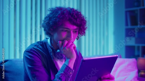 Digital Detox, Mental Health, Focus Mode. Man Relaxes on Sofa Using Tablet, Possibly Watching Streaming Content or Reading. Everyday Self-Care and Slow Living in the Digital Age