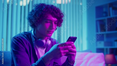 Digital Detox, Mental Health, Focus Mode. Man Relaxes on Sofa Scrolling Phone, Possibly Listening a Podcast or Browsing. Everyday Self-Care and Slow Living in the Digital Age