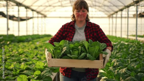 Woman smiling with wooden crate of fresh greenhouse vegetables. Suitable for organic produce, farming, healthy eating, grocery, and sustainability concepts.