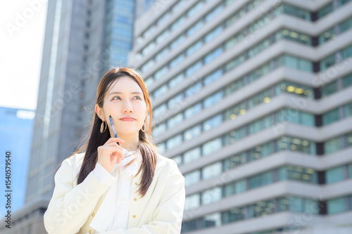 ビジネス街の中で遠くを見つめるように考える白ジャケットの女性が印象的な朝