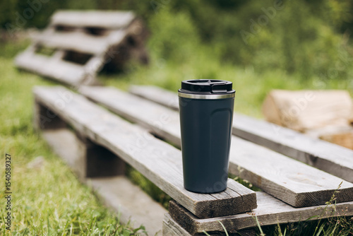 Stainless steel thermos cup outdoors on wooden bench