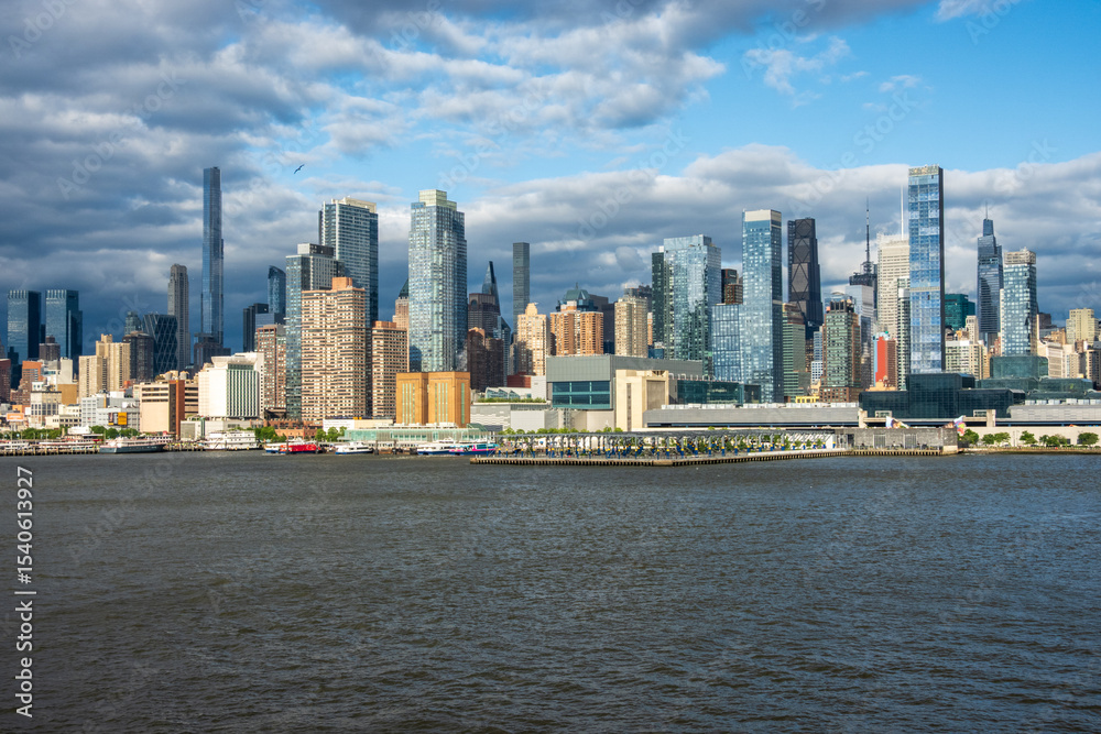 Fototapeta premium New York, NY - 18 May 2025: Tall office and apartment buidlings along the waterfront in Manhattan by Pier 78 and ferry terminal