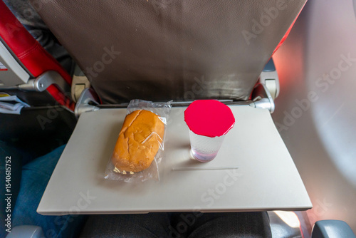 Airplane Meal with Bread and Water on Tray Table During Flight