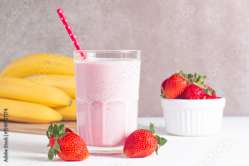 Glass of fresh strawberry milkshake, smoothie and fresh strawberries on white and wooden background. Healthy food and drink concept.
