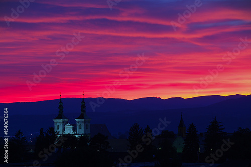 Silhouette of churches against a vibrant pink and purple sunset.