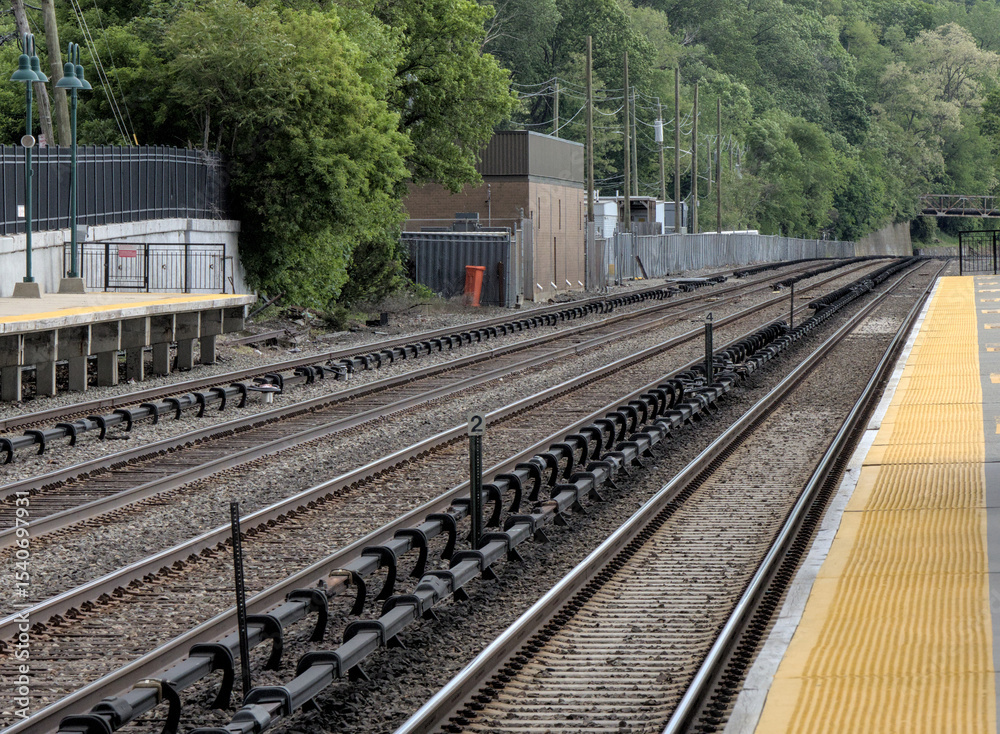 Fototapeta premium view down double train tracks on commuter rail line in upstate new york (travel commute rails track platform station stop) north metro subway