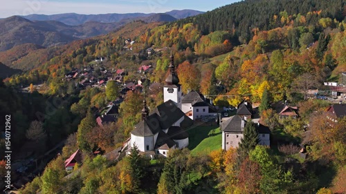 Flying over of fortified church in picturesque historic village Spania Dolina at autumn morning, Slovakia.