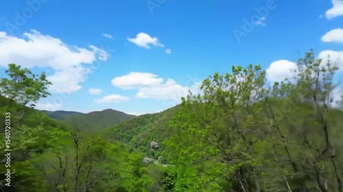 Green mountain range under a bright blue sky with puffy white clouds daylight