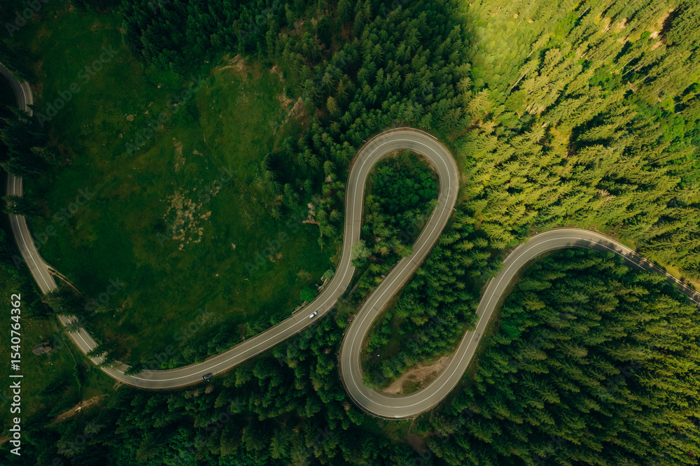 Fototapeta premium Top view or aerial of the road passing through the mountain and green forest.Curve asphalt road on mountain forest summer.