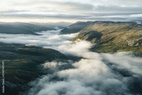 Clouds cascading over a mountain landscape during a tranquil morning, Aerial of of the clouds flowing over a mountain in Norway