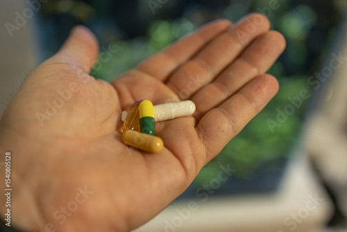 Hand holding various colorful capsules against blurry background