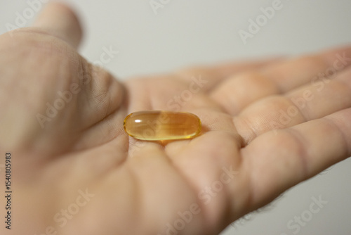 Hand holding single capsule with soft focus background
