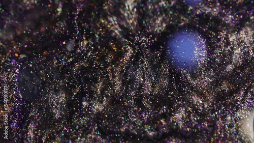 Macro abstract footage of a vivid blue sphere surrounded by shimmering black glitter particles. 