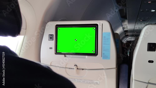 Airplane seatback with green screen monitor for in-flight entertainment, visible USB port, tray table, and part of passenger cabin interior, ideal for chroma key mockup or travel-related media design