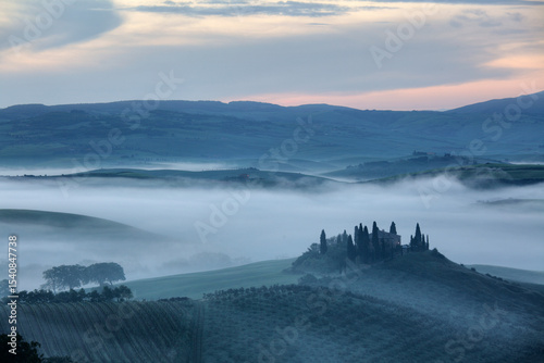 The Belvedere farmhouse in Val d’Orcia with early morning fog, San Quirico d'Orcia, Tuscany, Italy