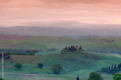The Belvedere farmhouse in Val d’Orcia with early morning fog, San Quirico d'Orcia, Tuscany, Italy