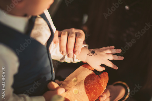 Enjoying creative fun at a lively family gathering with a child admiring a temporary tattoo while holding a plush toy in warm indoor lighting