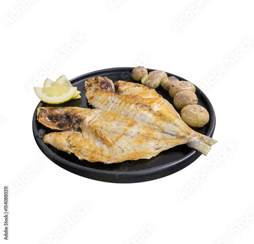 Grilled fish with potatoes and lemon on a black plate
