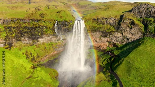 Seljalandsfoss Waterfall in Iceland, highlighted by a beautiful rainbow
