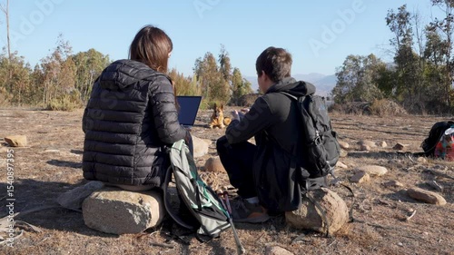 Two latin Americans hikers using laptop and smartphone on mountain top in Elqui Valley