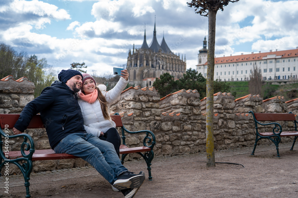 Obraz premium Pareja de turistas tomándose una selfie en una plaza de kutná hora, con la Catedral de fondo