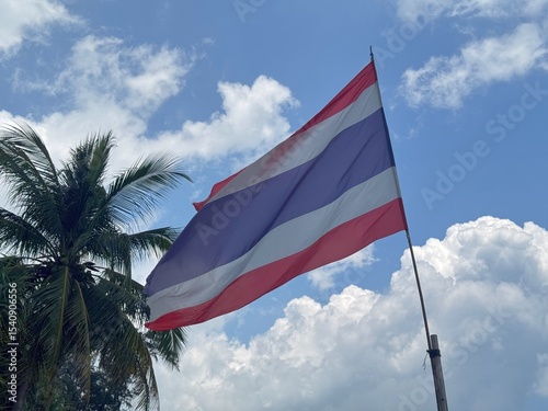 Thai Flag Over Karon Beach, Thailand. The flag of Thailand. Trairanga. Five horizontal stripes of red, white, blue, white and red, the middle stripe twice as wide as the others.