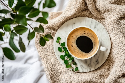 Coffee Cup Placed on Marble Plate With Greenery on a Cozy Blanket During Morn...