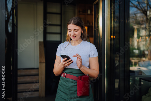 Canvas Print Waitress using smartphone at restaurant entrance, managing reservations and cust