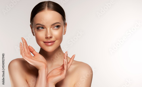 Beautiful young woman with clean fresh skin touching her face . Girl facial treatment . Cosmetology , beauty and spa . Female model, care concept