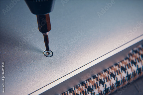 A close-up view of a screwdriver inserting a screw into a metallic surface, showcasing precision work.