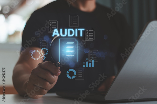 Audit business concept. Businessman using laptop and holding magnifying glass to check and evaluate financial statement, checklist auditing accounts within the organization.
