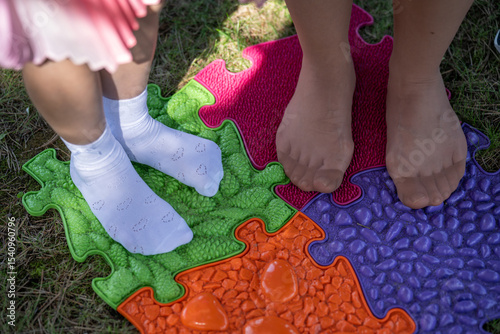 Wallpaper Mural Women's legs in stockings and children's feet in white heart-patterned socks standing on a plastic puzzle mat for foot massage.
 Torontodigital.ca
