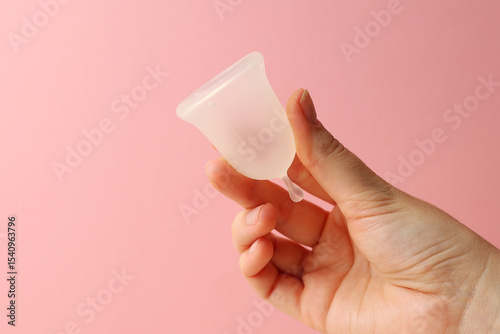 Eco-friendly menstrual cup in female hands on bright background