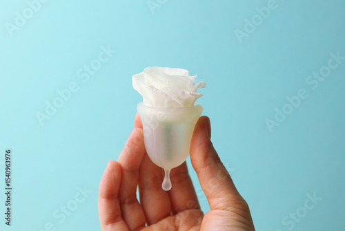 Eco-friendly menstrual cup in female hands on bright background