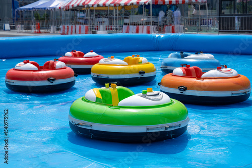 Colorful bumper boats floating in an amusement park pool on a sunny day during summer festivities