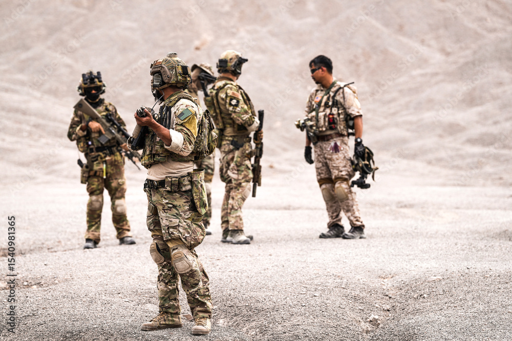 Fototapeta premium Special Forces Team Standing Together in Desert Mountain Terrain – Tactical Soldiers in Full Gear with Rifles, Communicating and Coordinating During a Military Operation or Training Mission