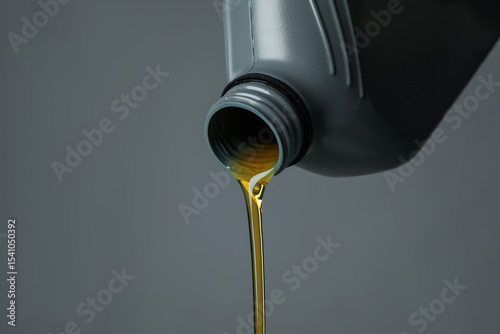 Fototapeta Naklejka Na Ścianę i Meble -  Pouring motor oil from canister on grey background, closeup. Space for text
