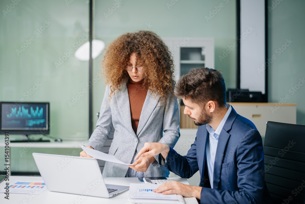 Fototapeta premium Professional man and woman collaborating on business strategy with laptops in office. Modern teamwork, corporate planning