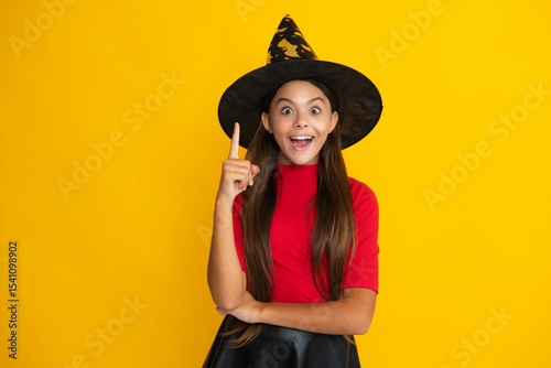 Happy child having fun on Halloween. Funny little girl with pumpkin on yellow studio background. Halloween witch girl. Cute teen witch. Happy Halloween. Portrait of an attractive Halloween child.