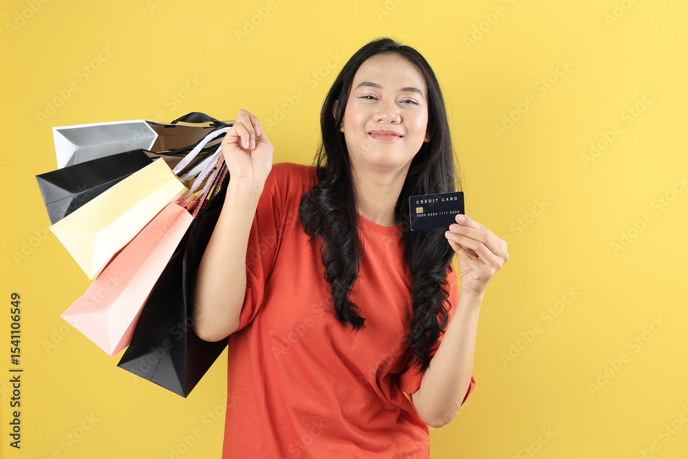 Naklejka premium Indonesian Young Girl Holding Lots of Shopping Bag on Right Hand and Black Credit card on Left Hand