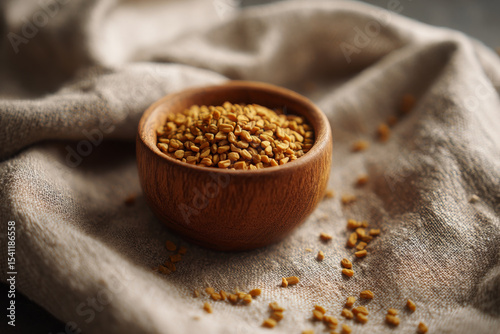 Fenugreek seed looks inviting inside wooden bowl placed on fabric