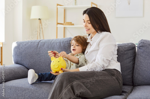 Cuadro en lienzo Mother and son, nanny woman sitting together on couch, interacting with yellow p
